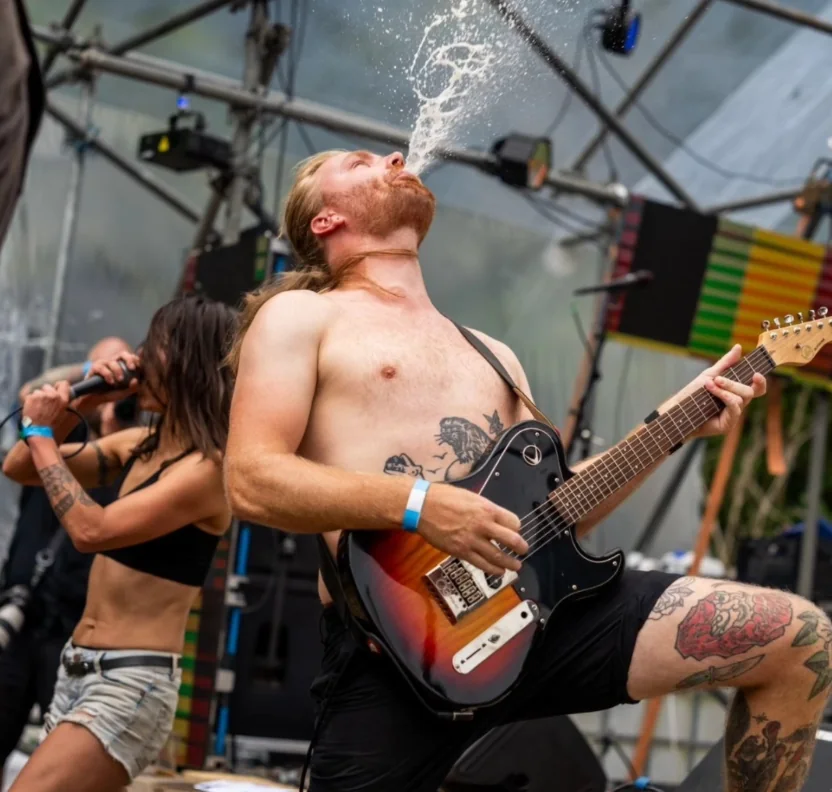 De gitarist van Bot Mes op de knieën, een straal bier de lucht in, de zangeres schreeuwend erachter